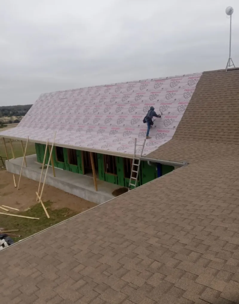 Worker preparing underlayment for a metal roof installation in Pearsall